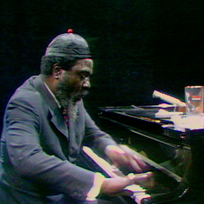 Thelonius Monk seated, fingers blurred in quick motion over piano keys, a still from Alain Gomis' documentary film Rewind & Play, courtesy Grasshopper Film
