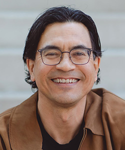 Duncan McCue wearing a brown leather jacket, smiling