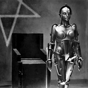 Metropolis, © Public Domain. Metropolis, © Public Domain. An armoured robot in German Expressionist style looks forward and stands upright in front of a black straight-backed armchair and Pentagram on the wall.