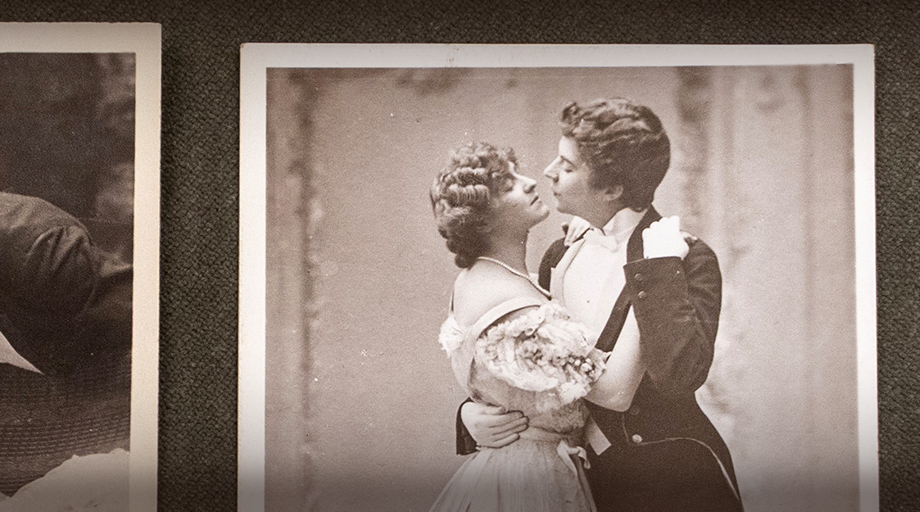 a photograph from the Lesbian Collection at UBC Library Rare Books and Special Collections. two women are embracing, one in a dress and the other in a suit.